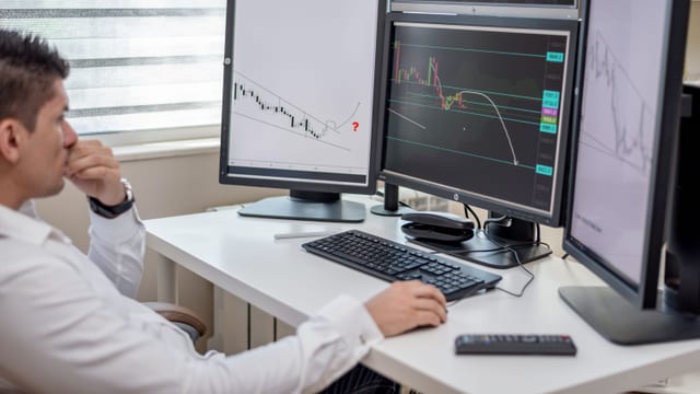 Financial analyst in front of trading screens