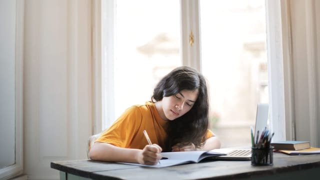 Student writing at her desk