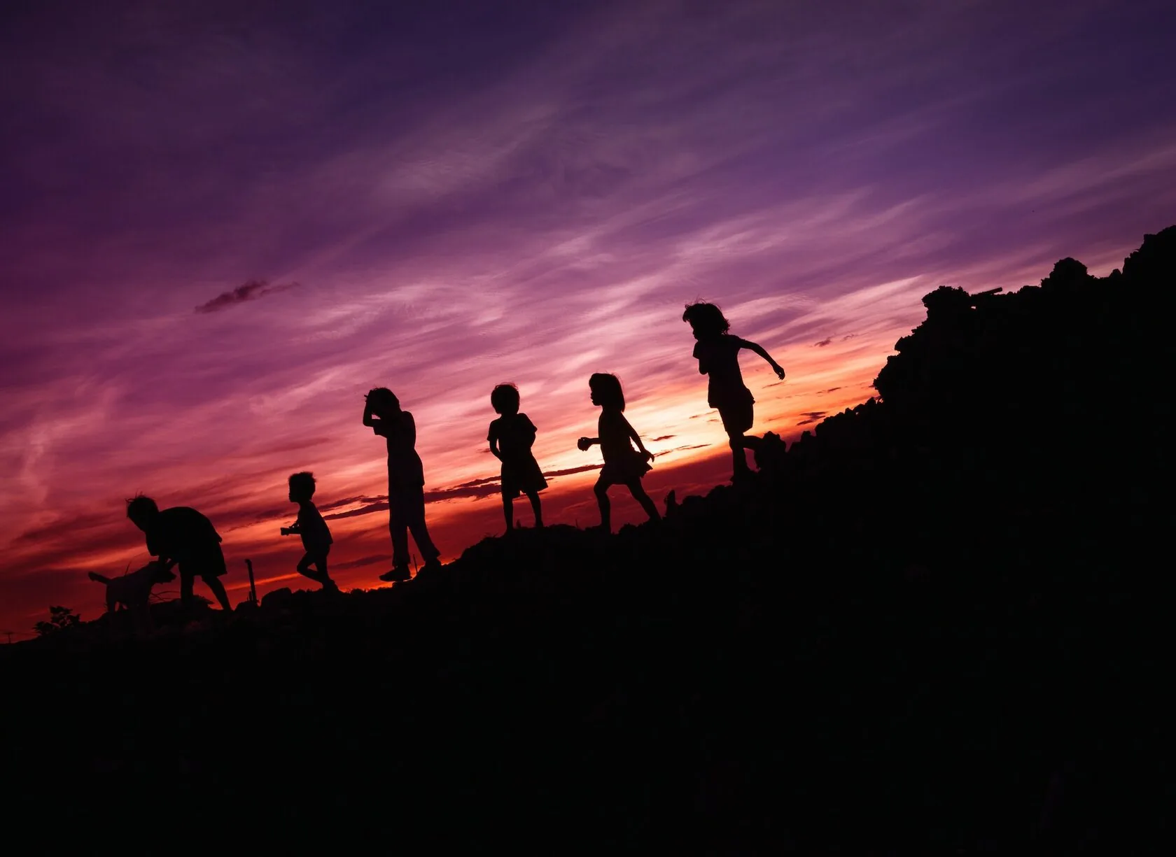 Silhouette of children running on a hill